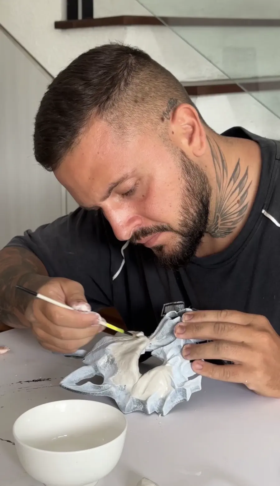 Alex Creator painting a white mask at a table