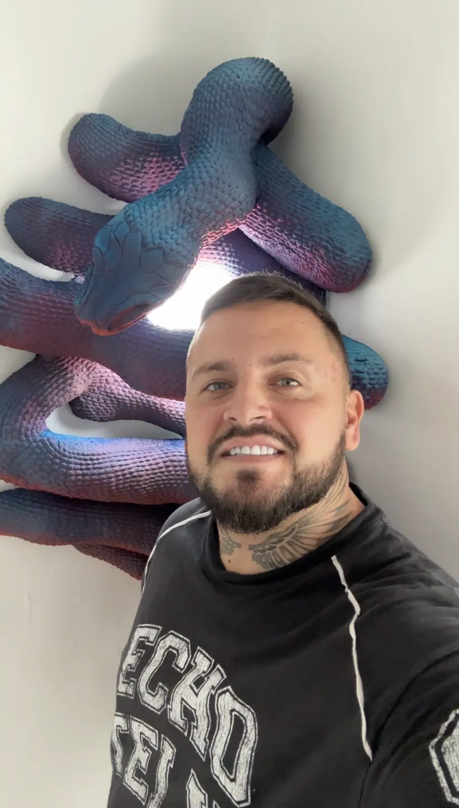 Alex Creator with a purple and blue snake wall sculpture