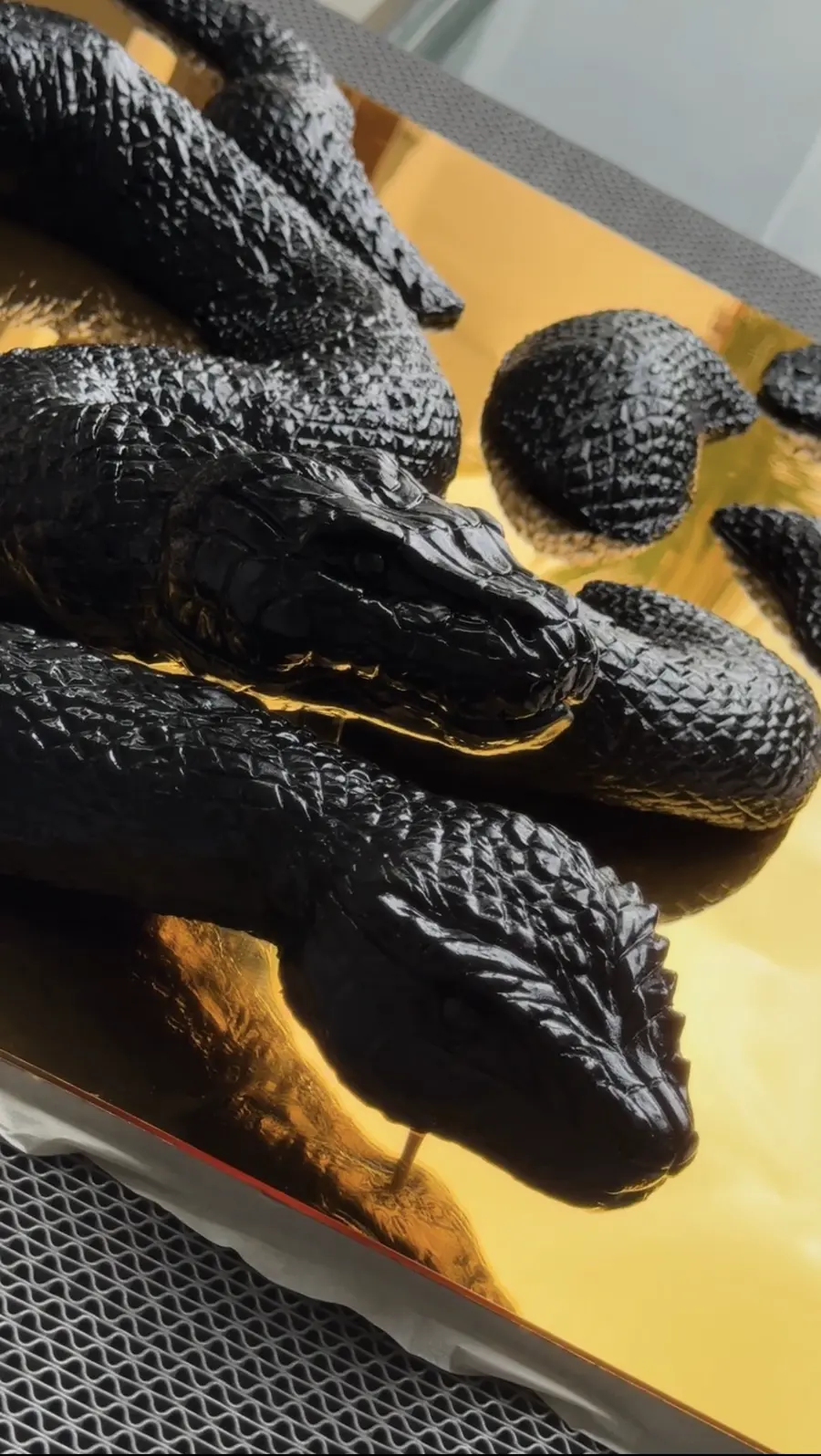 Black snake sculptures on a gold surface