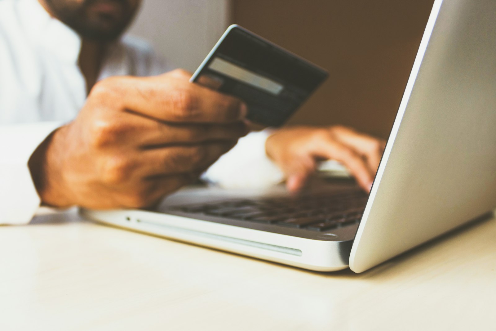 Person holding a payment card while typing on a laptop, representing UK shoppers checking out online during Black Friday and Cyber Monday.
