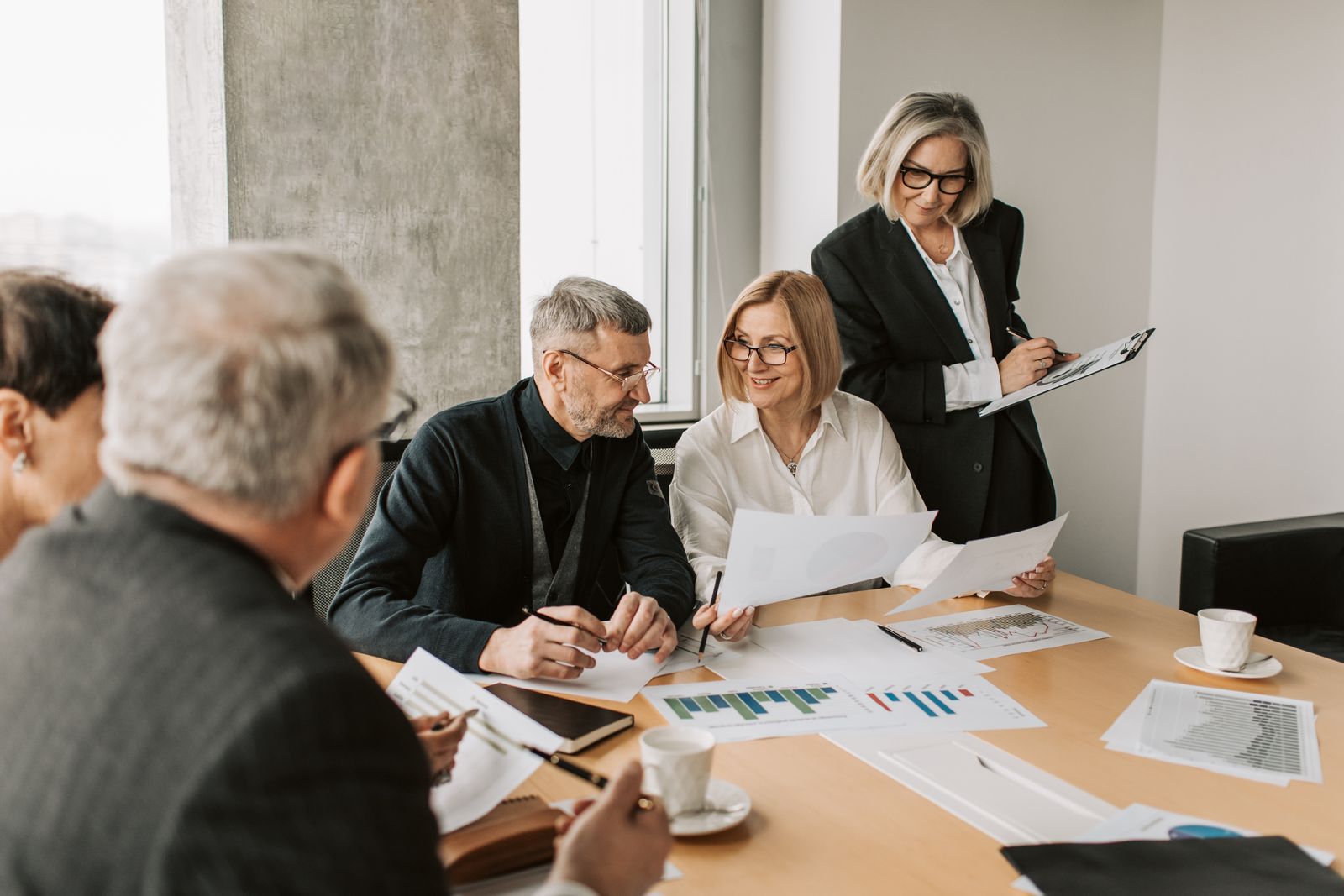 A marketing team around a conference table reviewing printed charts and reports, representing advertisers checking ChatGPT Ads measurement and brand suitability.