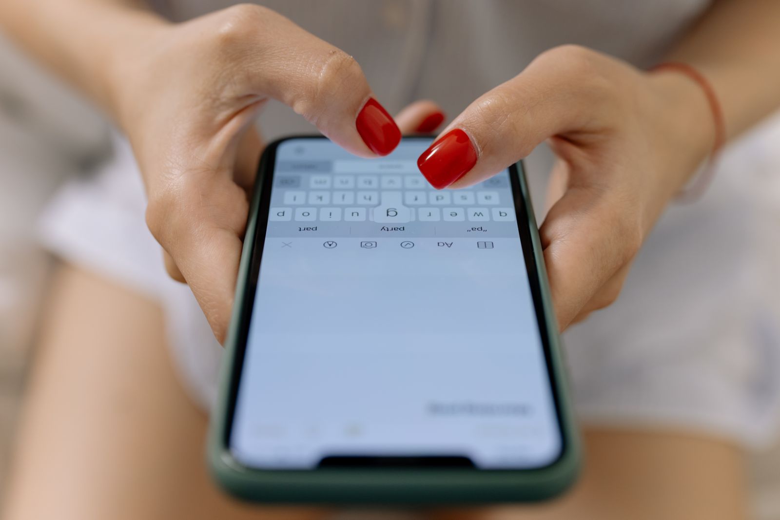 Close-up of a person's hands typing a message on a smartphone keyboard, representing a customer writing an online review.