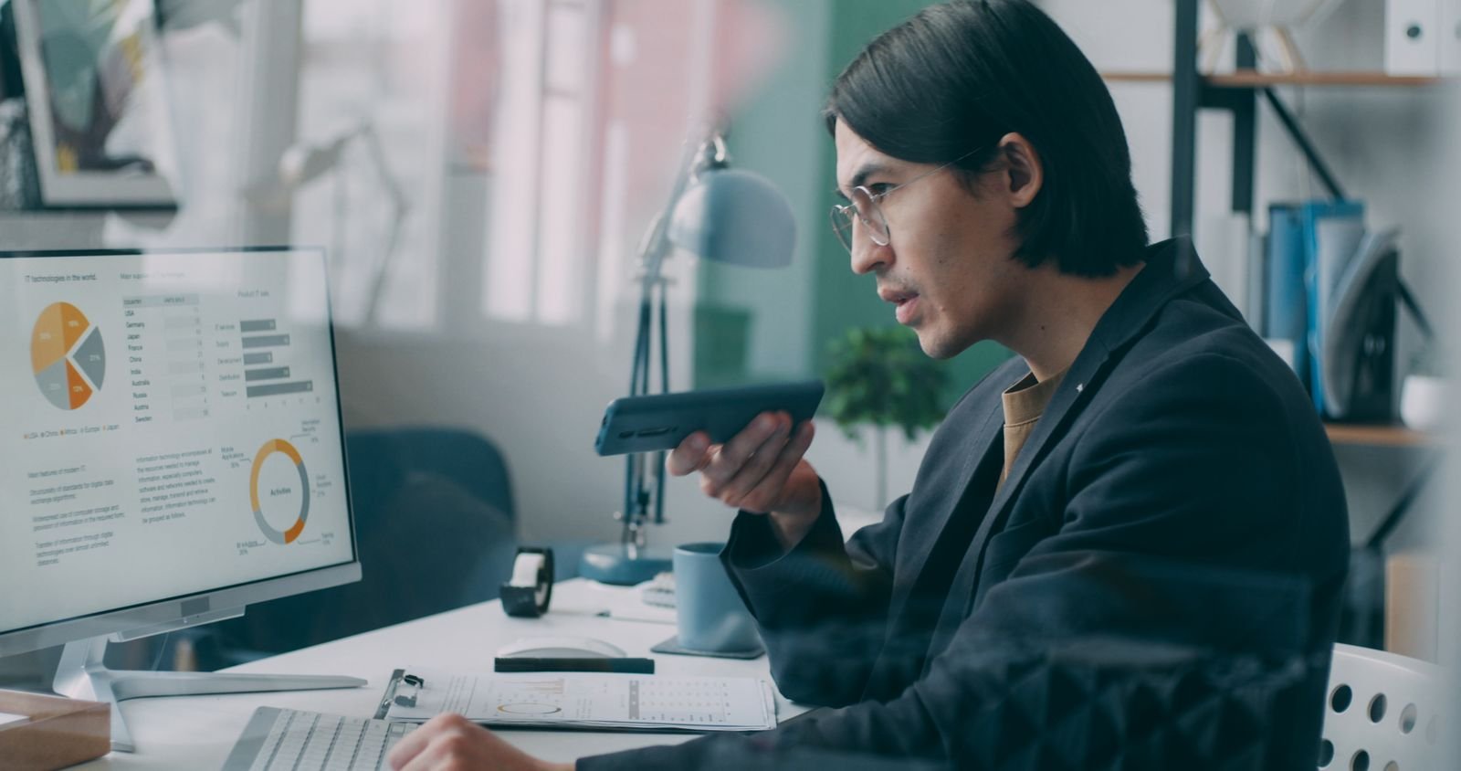 A professional in an office reviewing pie and line charts on a desktop monitor while on the phone, the kind of side-by-side review the All Conversions tab makes faster.
