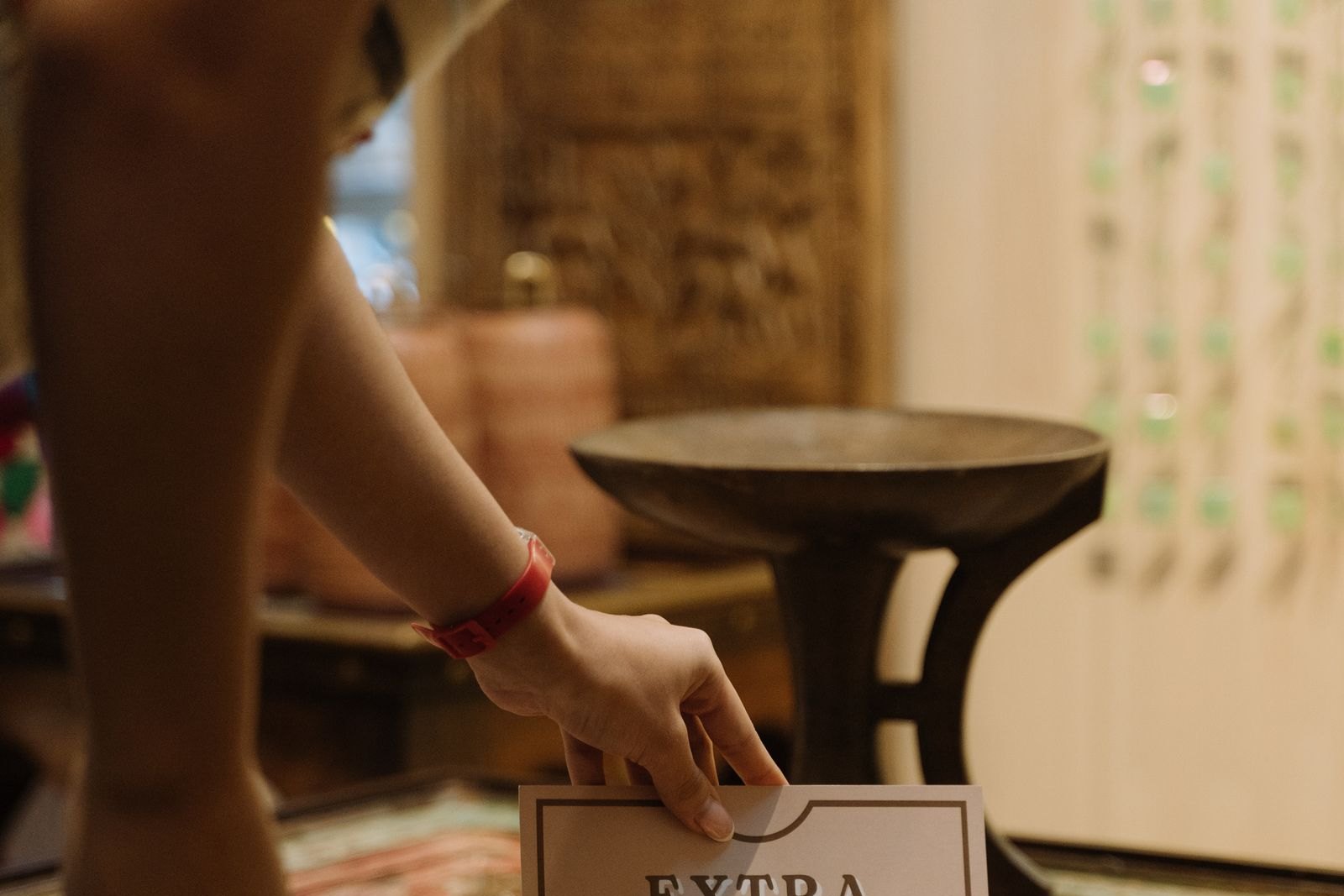Shop worker placing an "Extra 40% off final sales styles" sign on a wooden display table in a boutique, representing keeping in-store and website offers accurate.