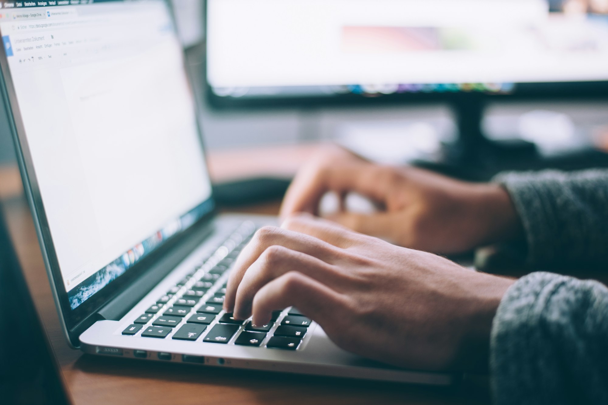 Hands typing on a laptop while editing a document, the kind of human review Google now treats as critical for AI-generated content.