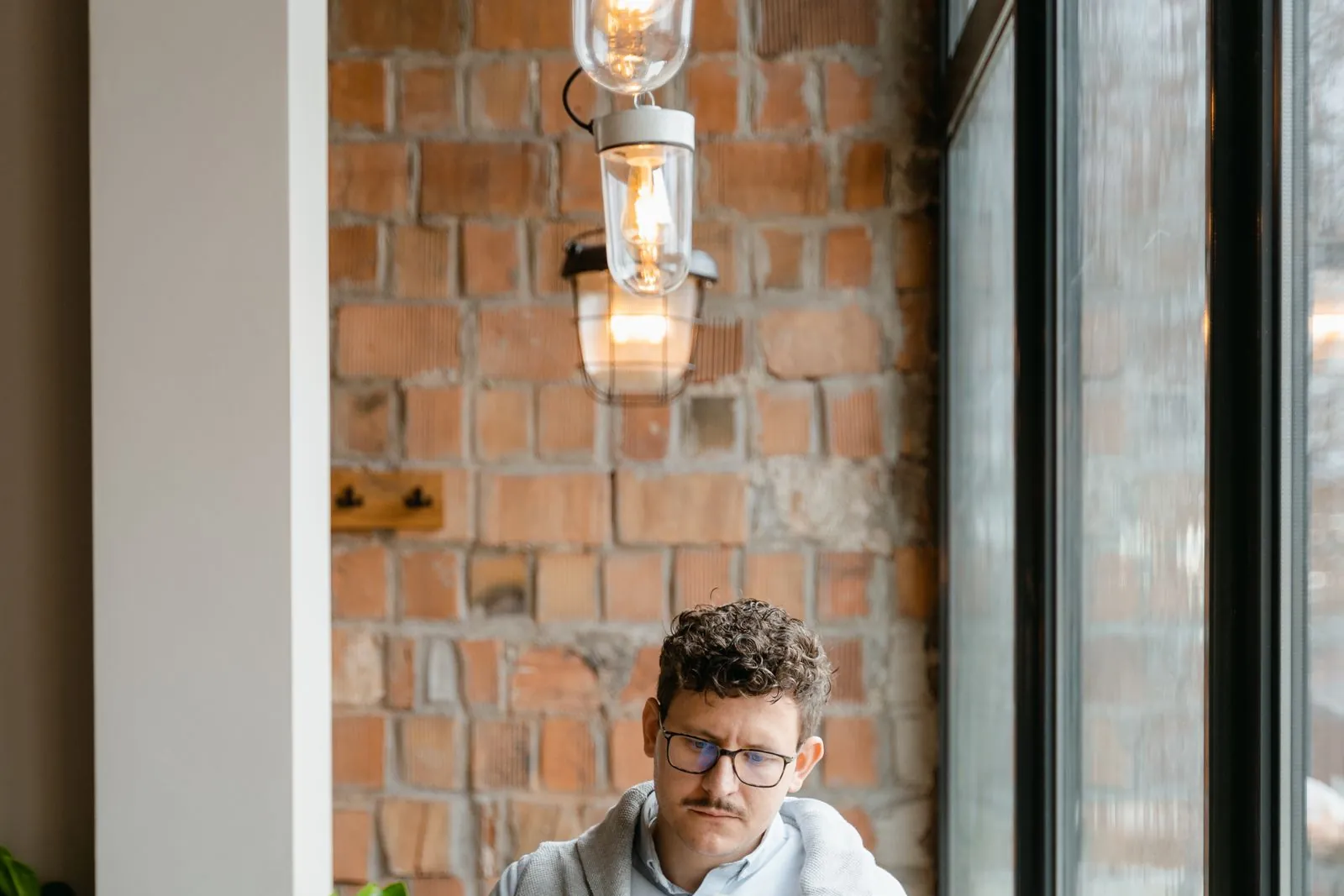 A man reading a newspaper at a cafe table with a coffee, a reminder that the KFC FCK ad ran as a single full-page print ad in two UK newspapers.