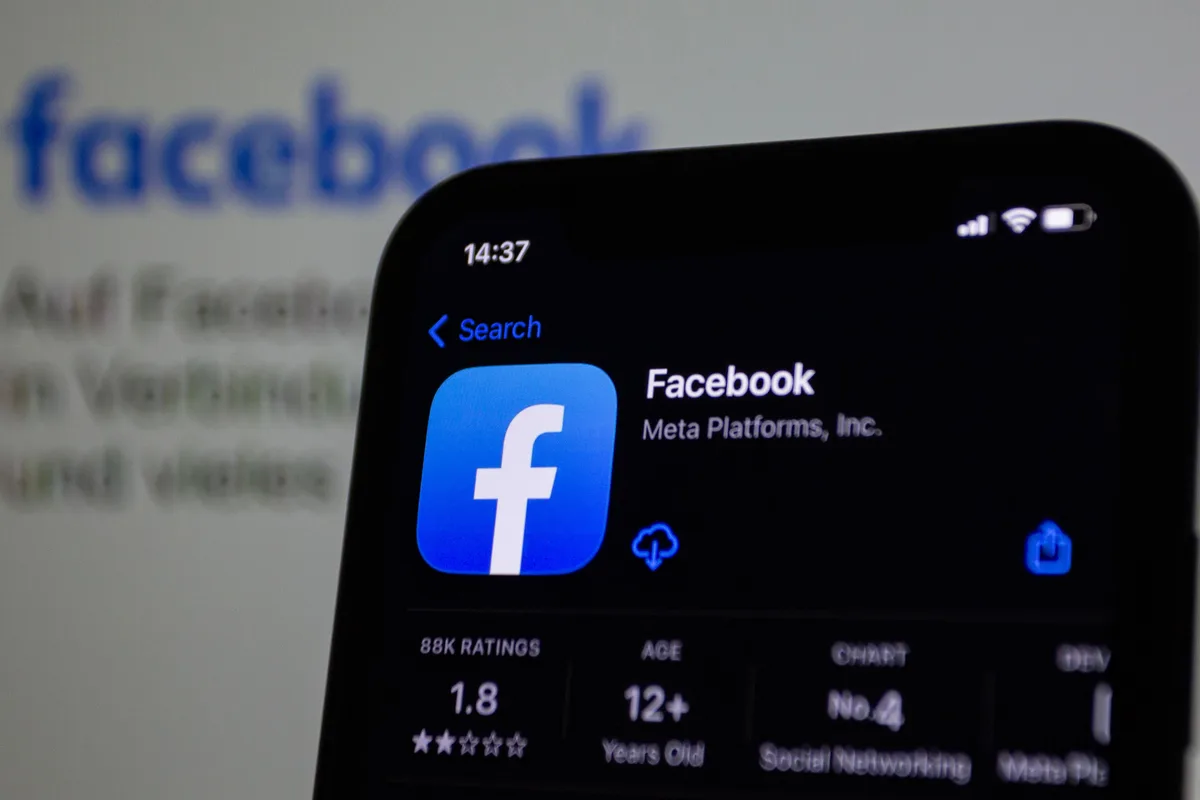 Facebook app open on a phone in front of a blurred Facebook logo