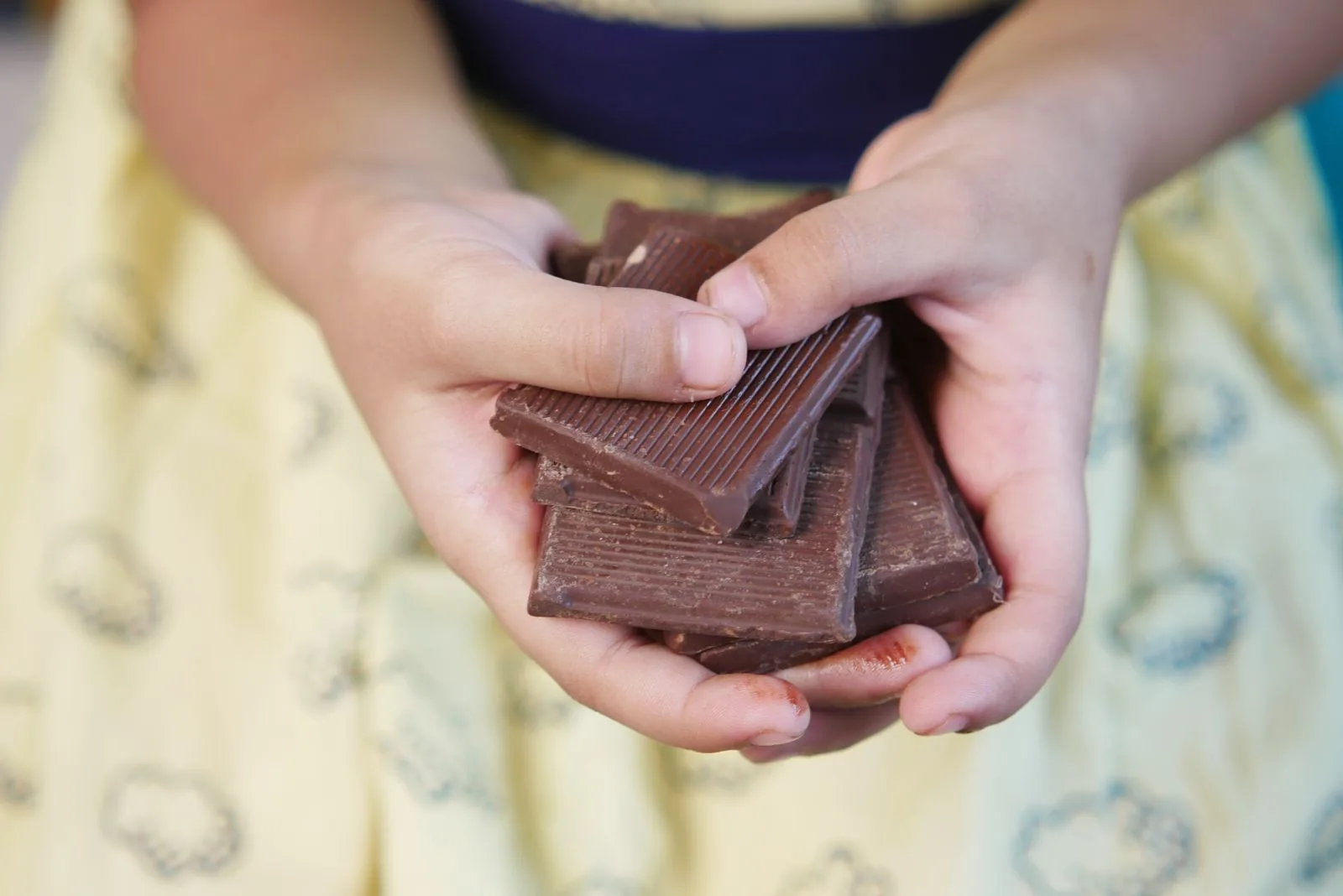 Two hands holding broken pieces of a milk chocolate bar, a nod to the £1 chocolate bar at the heart of Sainsbury's 1914 Christmas truce advert.