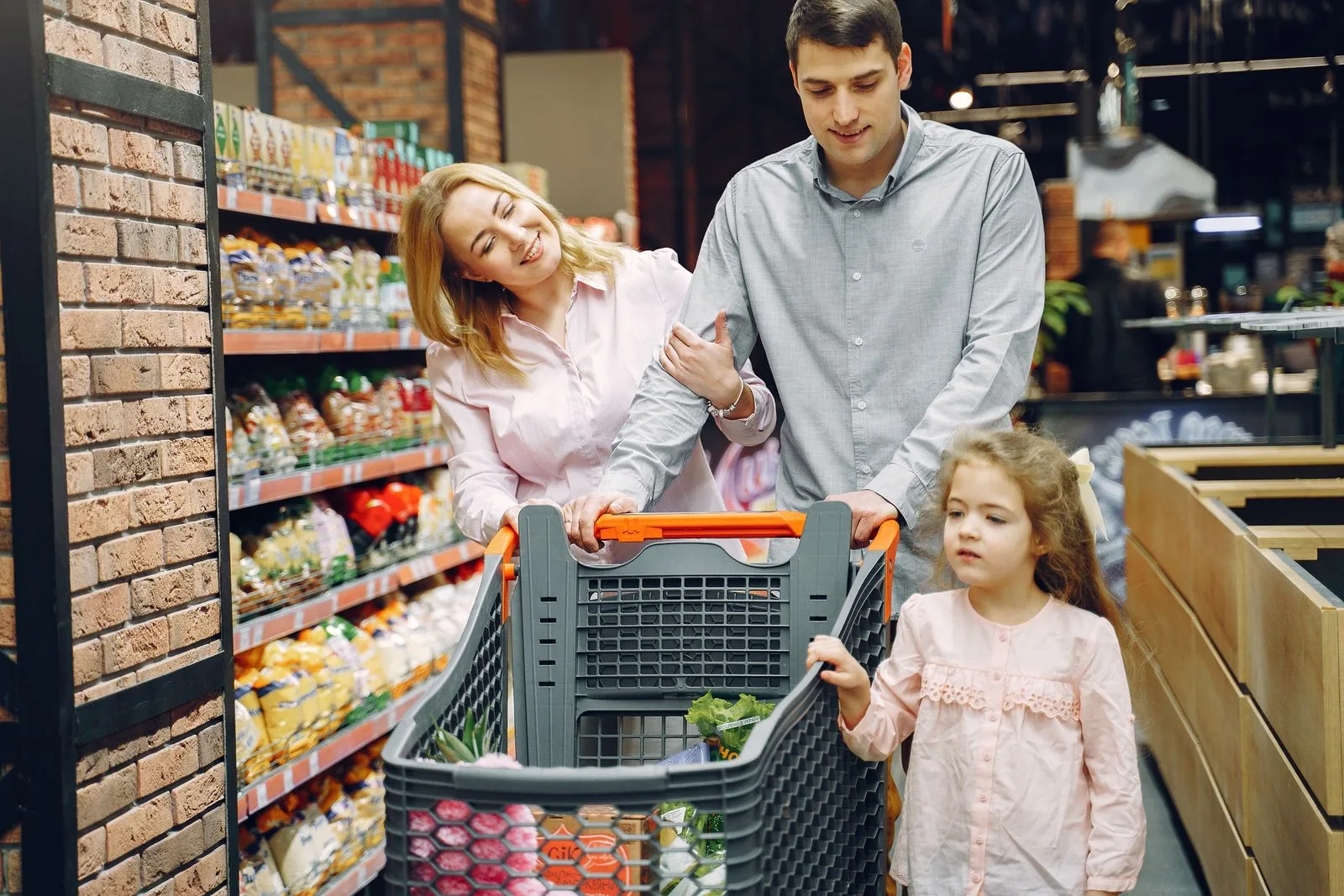 A smiling family pushing a trolley through a supermarket aisle with their young daughter, the Christmas shoppers that the Sainsbury's Christmas truce advert was competing to win.