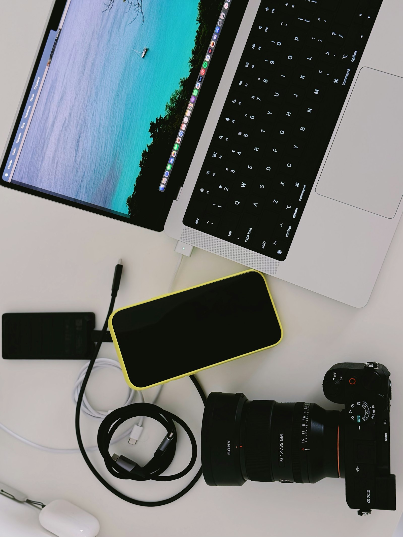Creator desk flat lay with laptop, camera, phone and portable drive, suggesting the production kit behind searchable short-form and long-form social content.