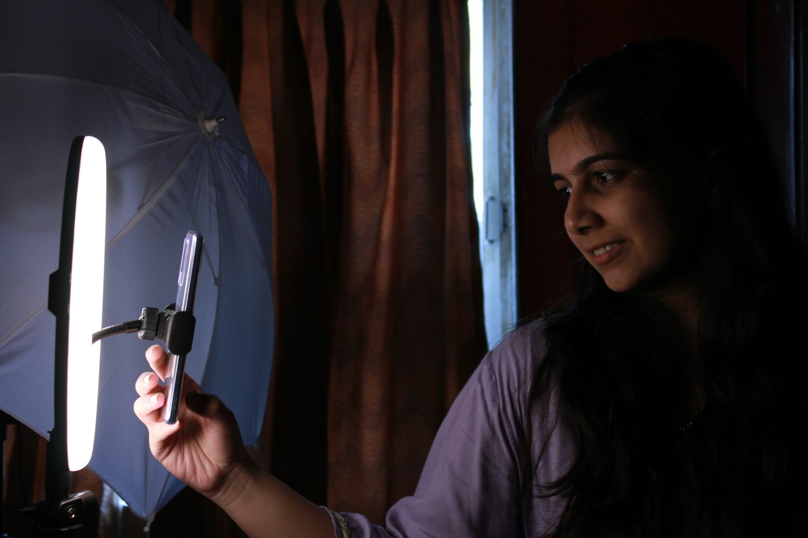 Creator filming short-form video on a smartphone under studio light, representing answer-first content built for social search.