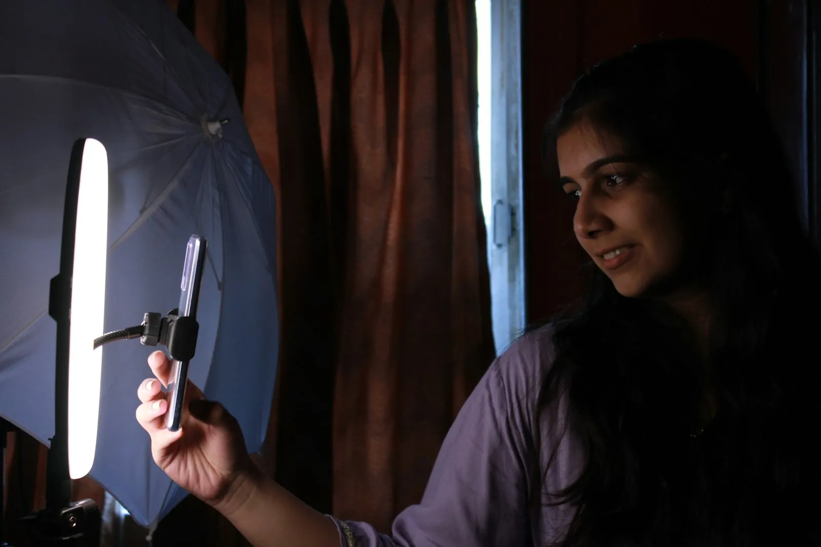 Creator filming short-form video on a smartphone under studio light, representing answer-first content built for social search.