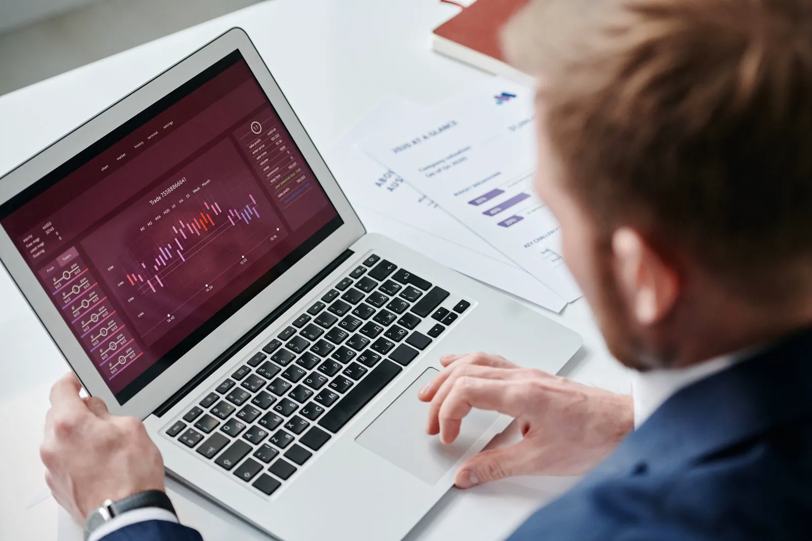 A man in a blue suit reviewing an analytics dashboard on a laptop at a white office desk, checking how the Threads placement performs in a UK business's Meta ads.